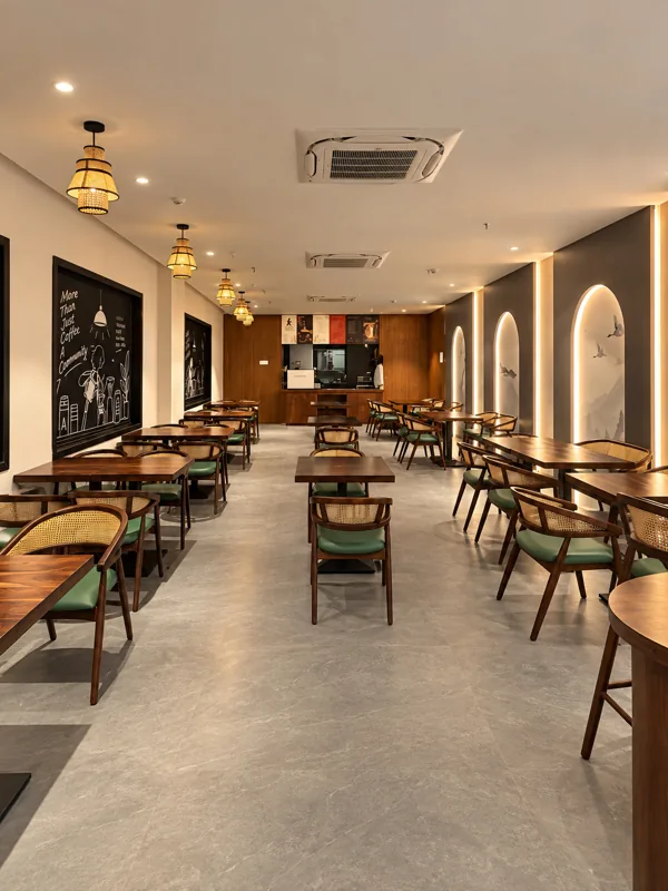 Pendant lamps, walnut tables and green-cushioned cane chairs inside Cafe Amara, Nizamabad